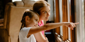 little girl pointing something outside from the window